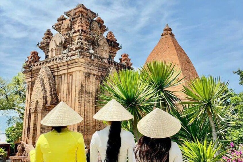 A temple with a pointed roof and intricate carvings, surrounded by lush greenery. 1