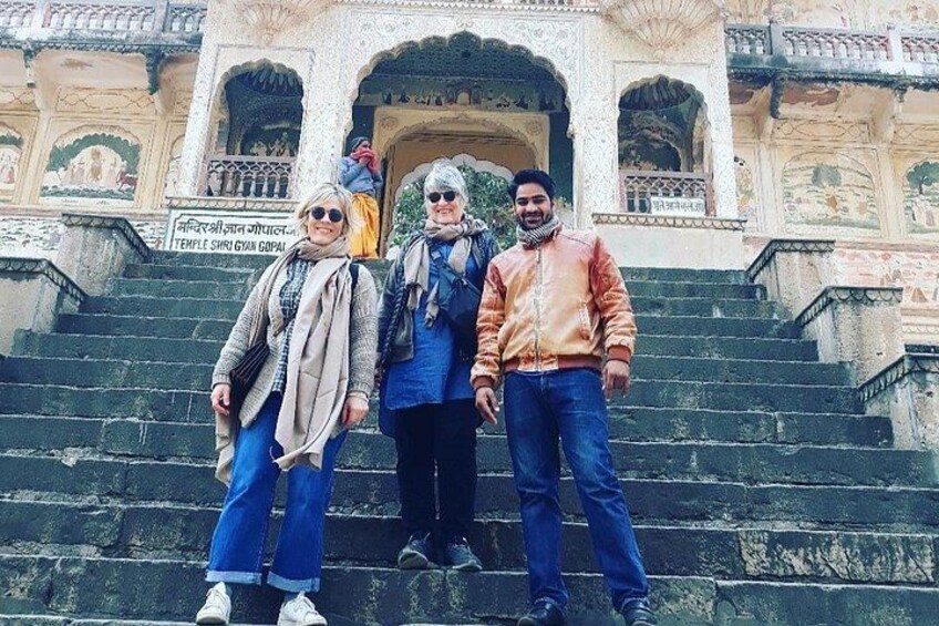Tres personas de pie sobre escalones de piedra frente a un templo con intrincadas esculturas. 1
