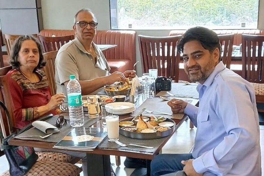 Un grupo de personas cenando en un restaurante, con una mesa servida con platos, vasos y una botella de agua. 2