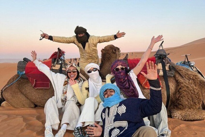 A group of people with camels in a desert landscape. 1