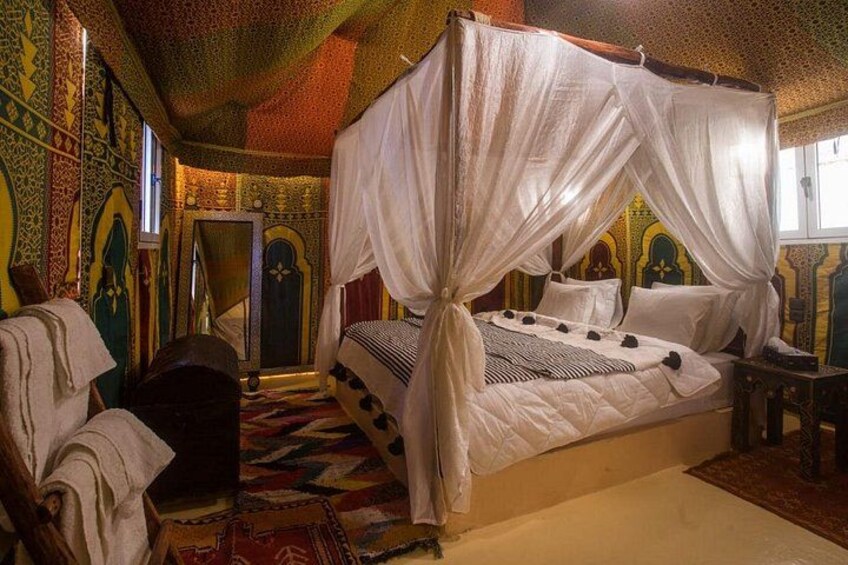 A traditional bed with a canopy, ornate walls, and a patterned rug. 3