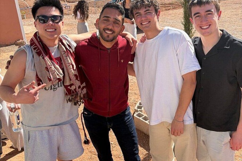 Four people standing outdoors, one wearing a red hoodie, another in a white t-shirt, and others in casual attire. 2