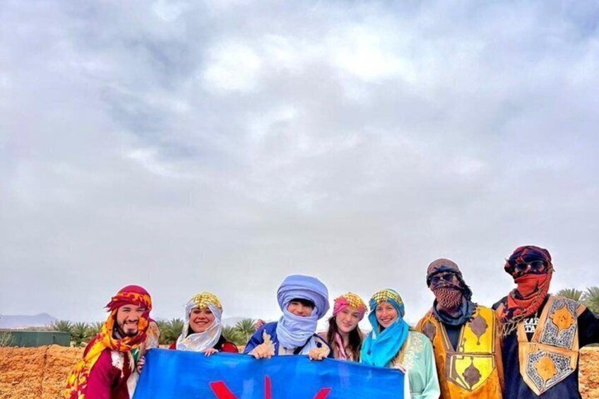 A group of people in traditional attire standing in a desert landscape. 5