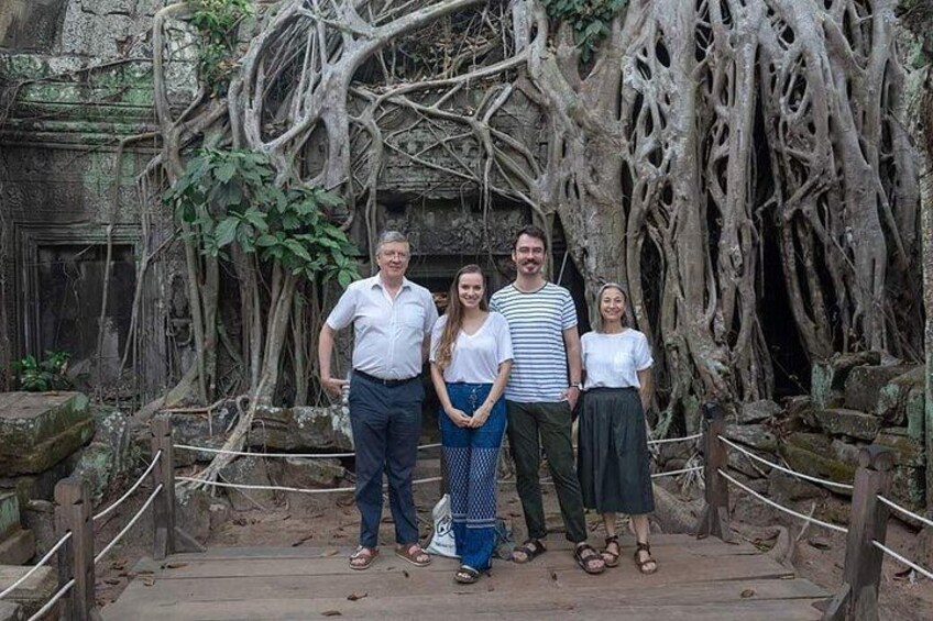 A group of people standing in front of ancient ruins with overgrown roots and a stone structure. 2