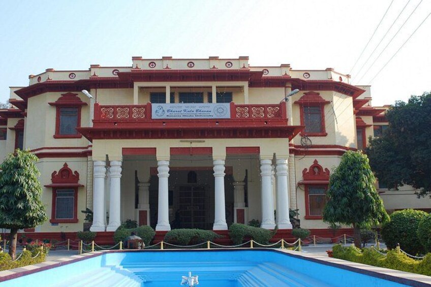 A building with a pool in front, featuring white columns and red trim. 5