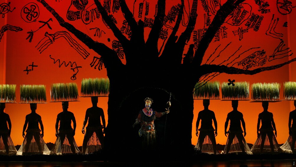 Un palcoscenico con figure in silhouette e un grande albero con disegni. 5
