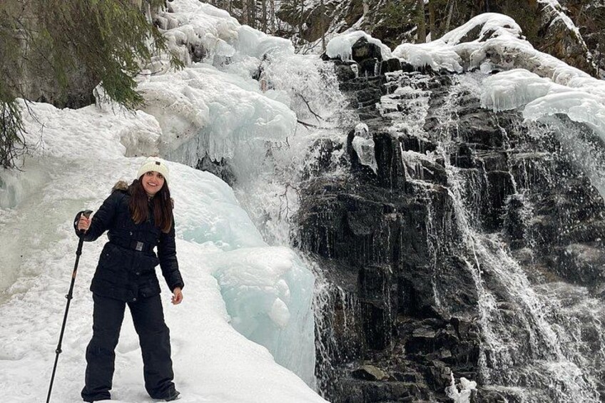 A person standing on snow with a waterfall in the background. 2