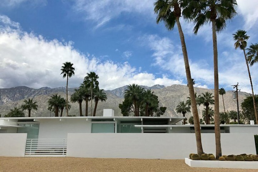 A modern building with palm trees and mountains in the background. 5