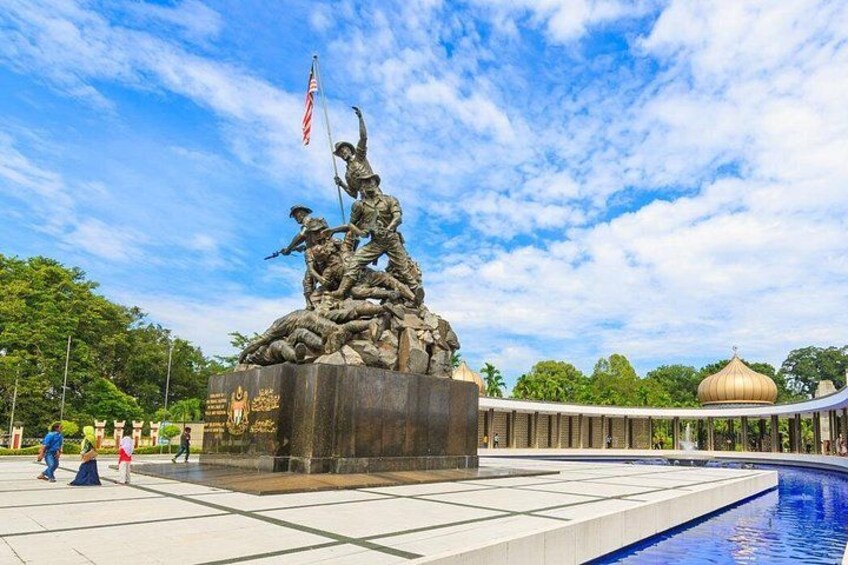 A statue of soldiers with an American flag, a pool, and a dome structure in the background. 4