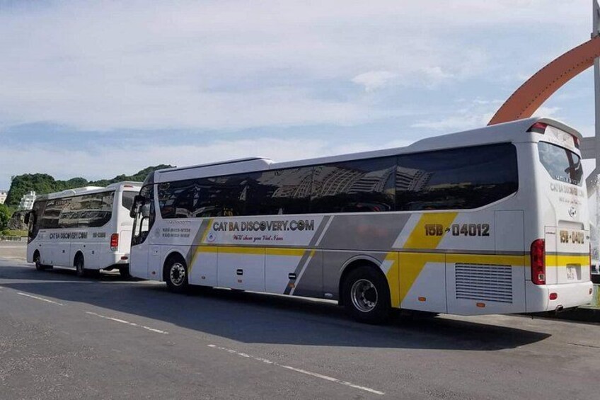 Two buses parked on a road with a clear sky. 4