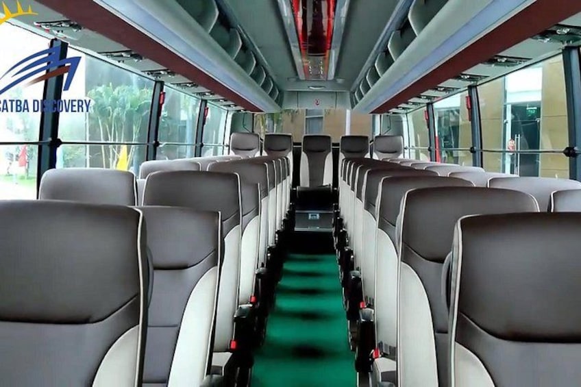 A bus interior with rows of seats and a green carpet. 2