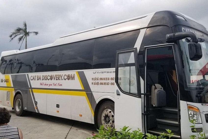 A white bus with yellow and black accents, parked with its door open. 1