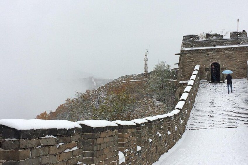 A snow-covered wall with a person holding an umbrella. 2