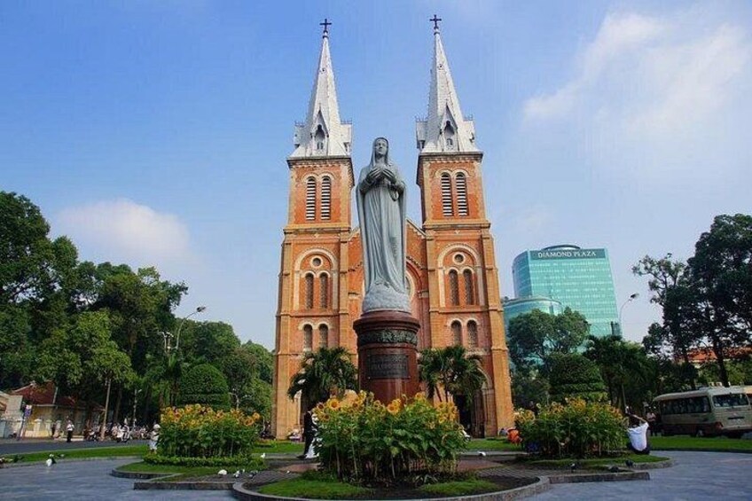 A historic church with twin towers and a statue in front. 4