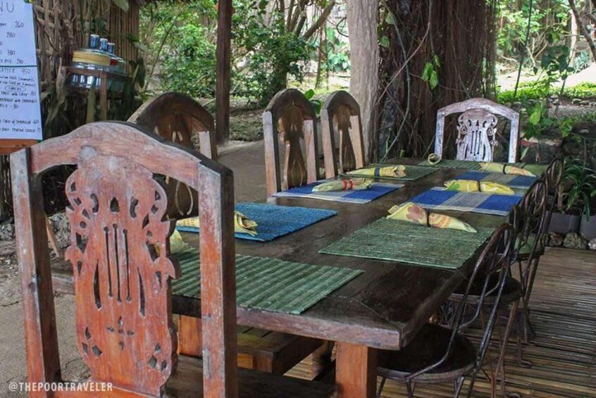 A rustic wooden table with blue placemats and a menu sign. 2