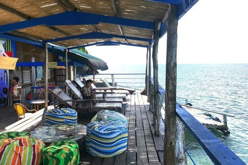 A wooden deck with colorful cushions, a covered area, and a view of the sea. 5