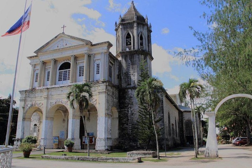 A colonial-style church with a bell tower, palm trees, and a flag. 2