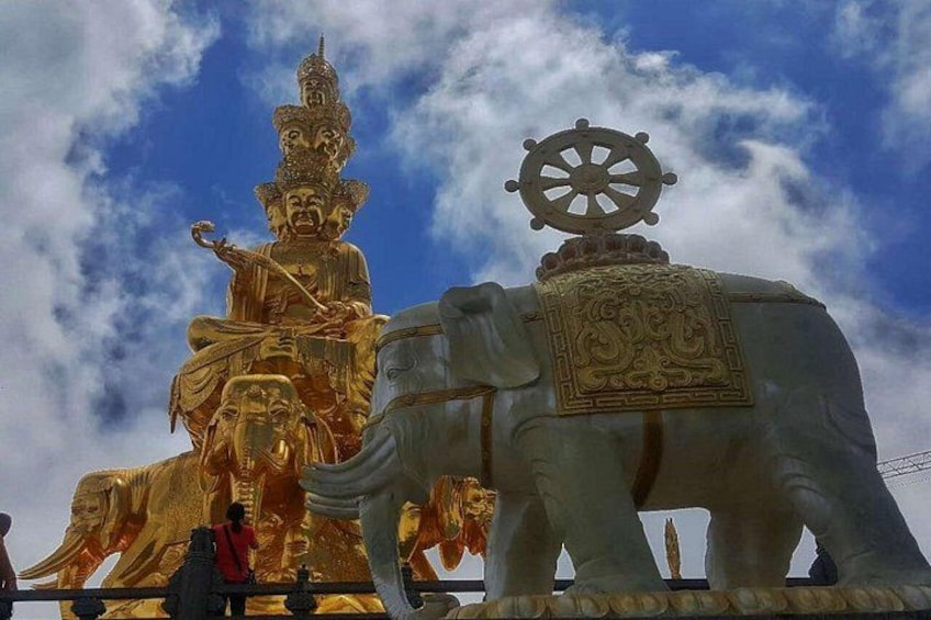 A golden Buddha statue on an elephant, with a wheel on top. 1