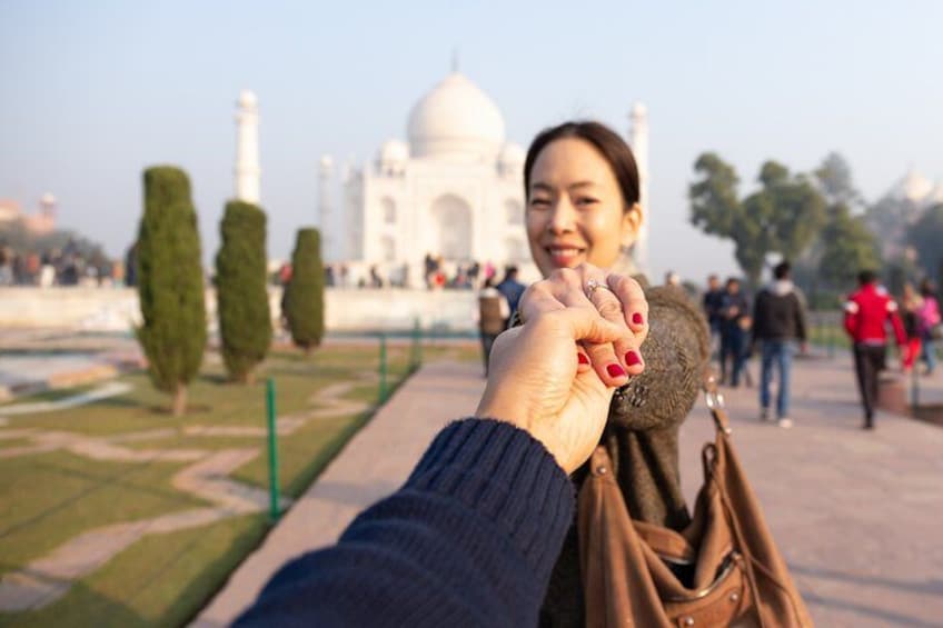 A person holding hands with another, with the Taj Mahal in the background. 2