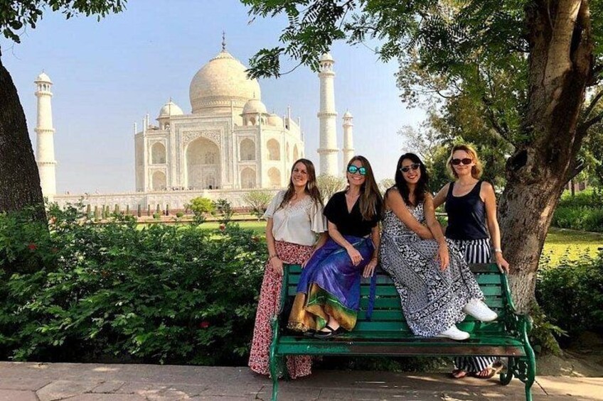 A group of people sitting on a bench with the Taj Mahal in the background. 3
