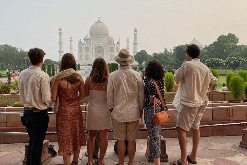 A group of people standing in a line, facing a large white domed building with minarets. 5