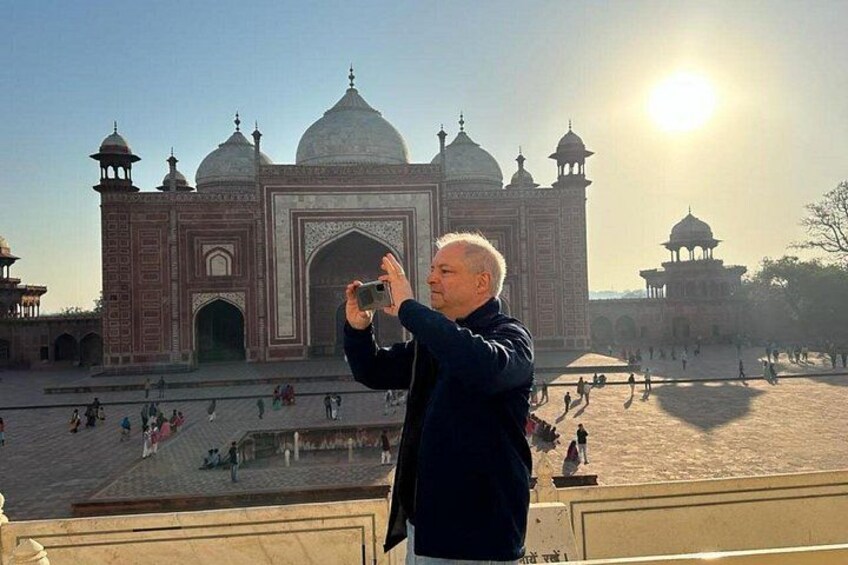 A person taking a photo of the Taj Mahal with the sun in the background. 3