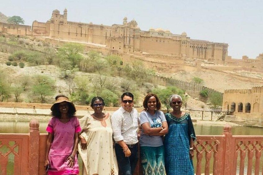 A group of people standing in front of a historical fort with a river in the background. 4