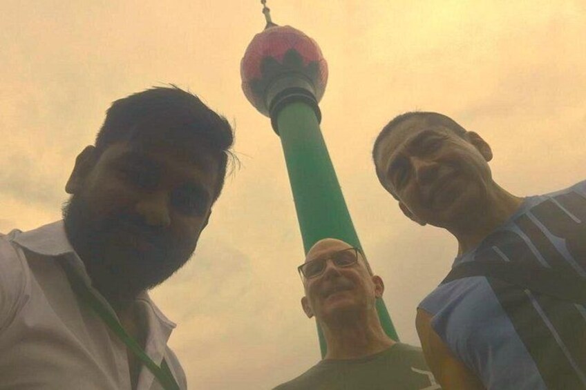 Two people standing near a tall tower with a spherical top, possibly a landmark. 5