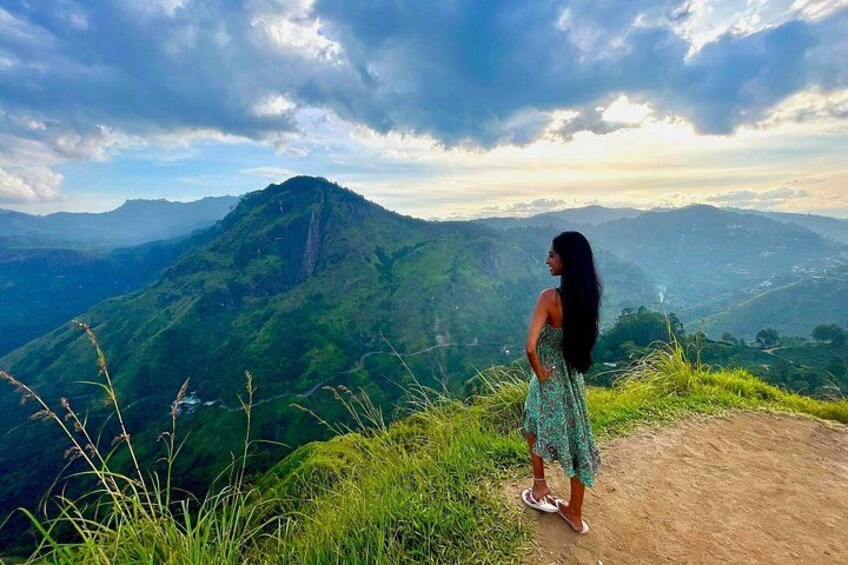 A person standing on a dirt path overlooking a mountainous landscape. 3