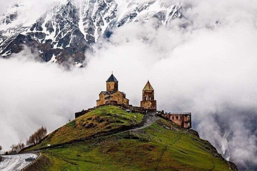 Una chiesa storica su una collina, con le montagne sullo sfondo. 1
