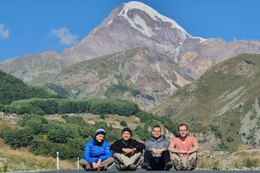 Un groupe de personnes est assis sur une corniche, avec une montagne en arrière-plan. 2