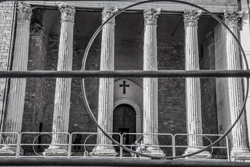 A building with classical columns, a cross, and a barred entrance. 3