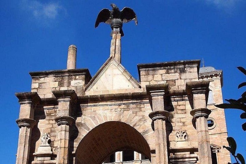 A stone building with a large arched entrance and a statue on top. 5
