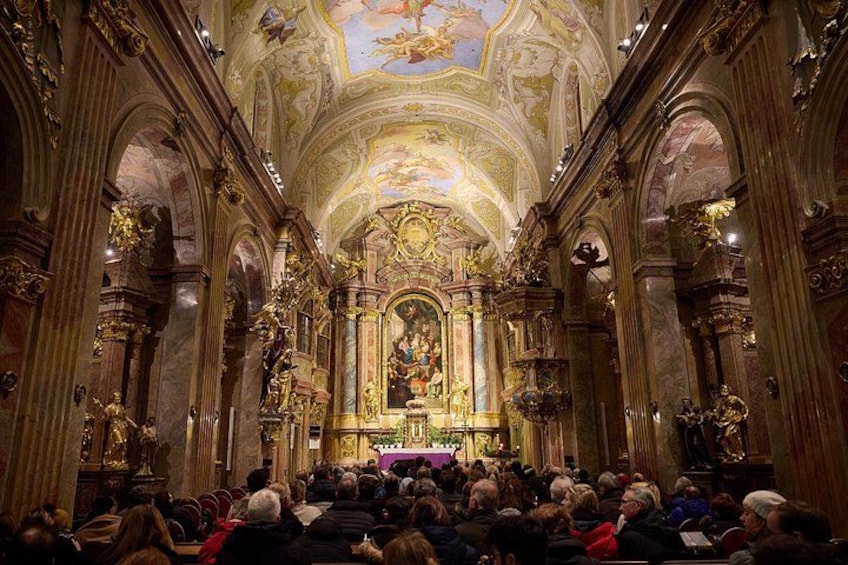 An ornate church interior with a central altar, high vaulted ceilings, and a congregation seated. 1