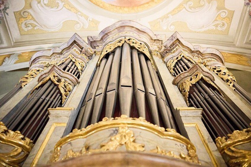 A grand organ with ornate gold detailing and a classical architectural ceiling. 4