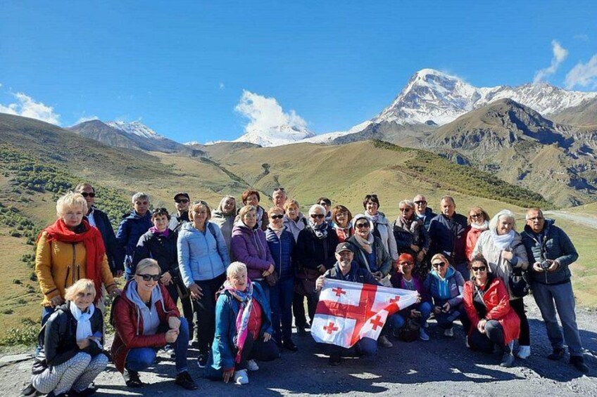 Un grupo de personas posando con una bandera suiza en un paisaje montañoso. 1