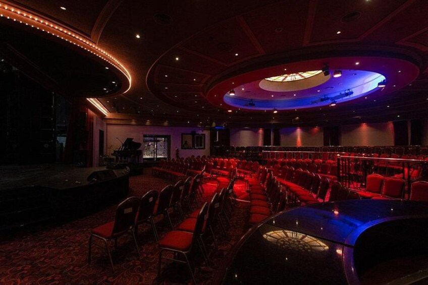 A theater with red seats, a stage, and a circular ceiling design. 2