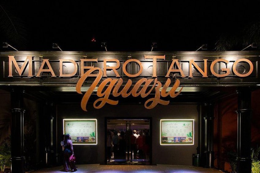 The exterior of Madero Tango Iguazu with illuminated signage and two digital displays. 1