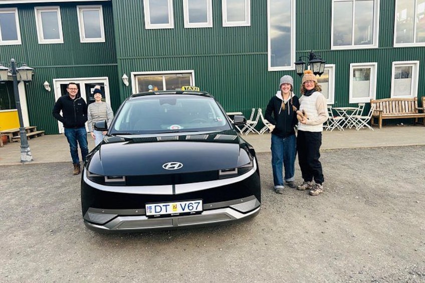 Un'auto nera con il segnale di taxi parcheggiata davanti a un edificio verde. 3