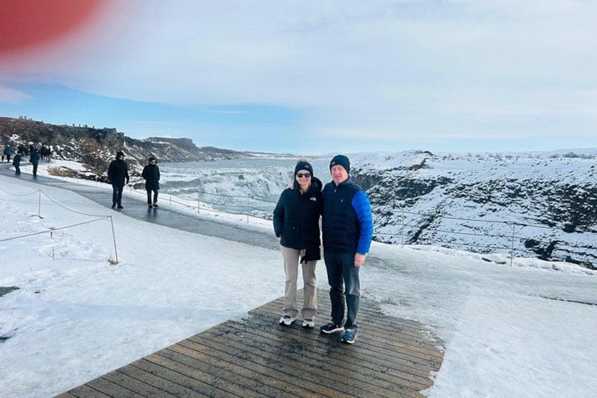 Paesaggio innevato con una passerella in legno, persone che passeggiano e una costa lontana. 5