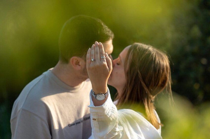 A couple embracing outdoors with greenery in the background. 3