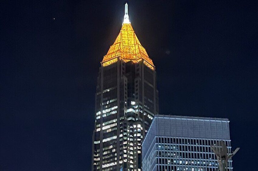 Un edificio alto con una aguja iluminada y una fachada brillante. 4