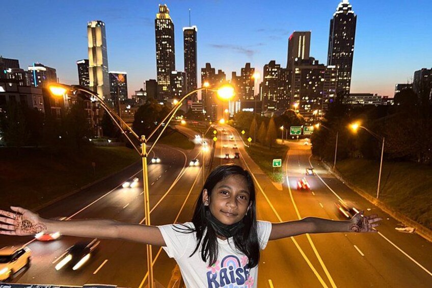 A city skyline at dusk with illuminated buildings and a highway with vehicles. 5