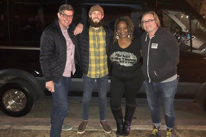 Four people standing in front of a vehicle. 2