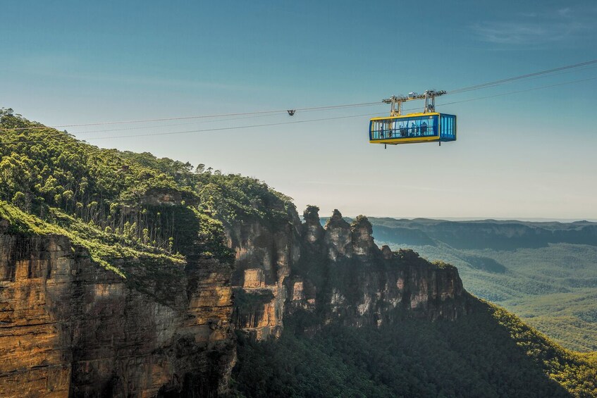 A cable car system in a mountainous area with rocky cliffs and dense greenery. 5