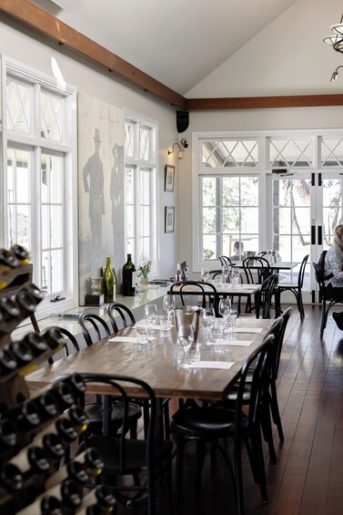 An indoor dining area with wooden tables, black chairs, and large windows. 5