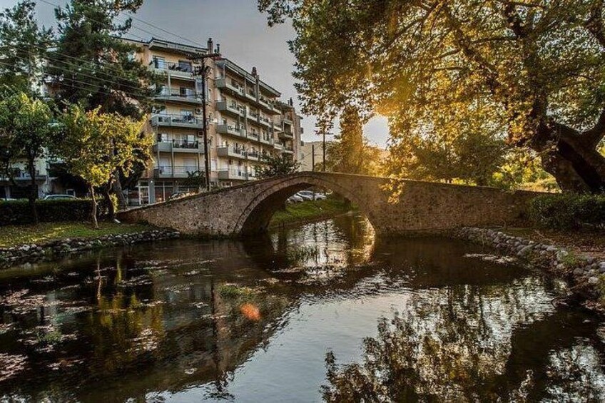 Un puente de piedra sobre un río tranquilo, rodeado de árboles y edificios. 3