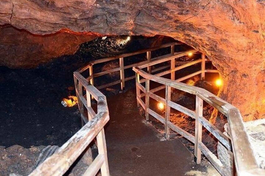 A cave with wooden railings and a pathway leading into the darkness. 3