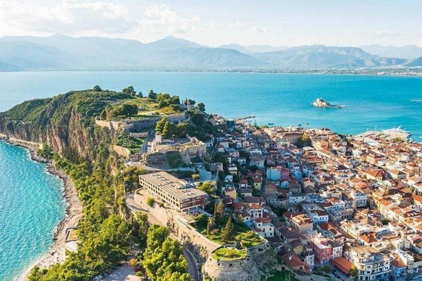 A coastal town with a historic fortification, a dense cluster of buildings, and a clear blue sea. 3