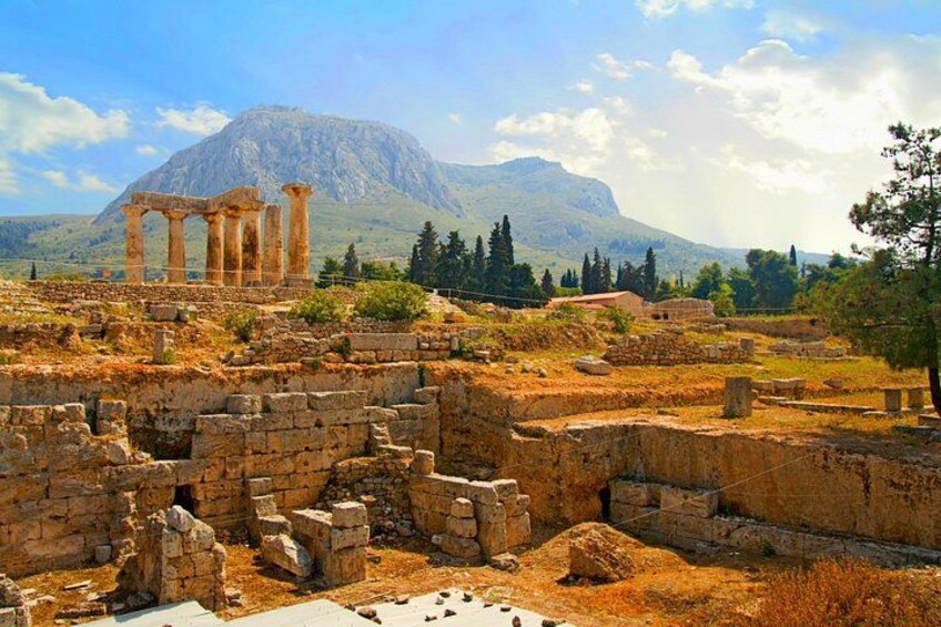 Ancient ruins with columns, a mountain, and sparse vegetation. 4